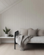 A bright Scandinavian garage loft with white walls, pale oak flooring, and a minimalist black metal frame daybed, accented with a light grey throw and a simple potted snake plant on a white floating shelf. — close-up of textures and materials