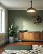 Mid-Century Modern home gym with a muted olive green accent wall, light gray walls, a Sputnik-style pendant light, and a teak-veneered credenza. A yoga mat is laid out on a geometric wool rug, with a snake plant in a ceramic planter. — alternate angle