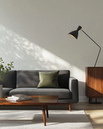 A minimalist Mid-Century Modern family room featuring a low-slung charcoal grey sofa, a walnut coffee table with clean lines, and an iconic Arco Floor Lamp, complemented by a muted olive green accent pillow and a simple credenza. — styling and décor detail