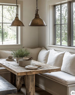 A warm and inviting farmhouse breakfast nook featuring a rustic reclaimed wood table, a cream banquette with linen cushions, and two aged bronze pendant lights hanging over the table, with soft morning light streaming through a window. — close-up of textures and materials