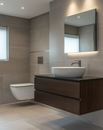 Modern bathroom with a floating dark wood vanity, white vessel sink, and large format grey wall tiles. Integrated LED mirror lighting and recessed ceiling lights illuminate the space, complemented by polished chrome fixtures. — styling and décor detail