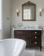 Traditional bathroom featuring a white clawfoot tub, a dark wood console vanity with a Carrara marble top, polished nickel fixtures, and an ornate gilded mirror above the sink, all under warm sconce lighting. — alternate angle