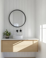 A bright Scandinavian powder room with white walls, a light wood floating vanity, a minimalist round mirror, and a single black wall-mounted faucet, accented by a small green plant. — close-up of textures and materials