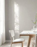 A bright Scandinavian dining room featuring a light birch wood dining table, minimalist white chairs, a simple linen tablecloth, and a clear glass vase with a single green branch, all set against soft grey walls. — close-up of textures and materials