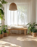 A bright Scandinavian sunroom featuring light oak flooring, a minimalist birch wood bench, and a rattan pendant light. Natural linen curtains filter the sunlight, while a faux sheepskin throw and various green plants in unglazed ceramic pots add texture and life. — close-up of textures and materials