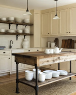 A cozy rustic kitchen featuring creamy off-white cabinets, a reclaimed wood island, and open shelving displaying white stoneware. Wrought iron hardware and a sisal runner add to the warm, inviting atmosphere, with natural light streaming in. — close-up of textures and materials