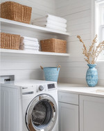Small coastal laundry room featuring white shiplap walls, a stackable washer and dryer, open shelving with woven baskets, and a light quartz countertop with a small farmhouse sink. Soft blue accents are visible in a decorative ceramic vase. — close-up of textures and materials