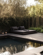 A serene Japandi pool area featuring a dark-tiled swimming pool surrounded by smooth concrete pavers and a low-slung teak daybed with charcoal cushions. Subtle solar-powered lanterns glow amidst pet-friendly green groundcover and slender bamboo plants. — close-up of textures and materials