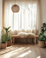 A bright Scandinavian sunroom featuring light oak flooring, a minimalist birch wood bench, and a rattan pendant light. Natural linen curtains filter the sunlight, while a faux sheepskin throw and various green plants in unglazed ceramic pots add texture and life. — styling and décor detail