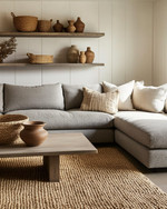 A Modern Craft living room with a large, comfortable sectional sofa in a warm grey performance fabric, an oak coffee table with a matte finish, and a woven jute rug. Walls are painted in a soft off-white, complemented by shelves displaying hand-thrown ceramic vases and a large woven basket for storage. — close-up of textures and materials
