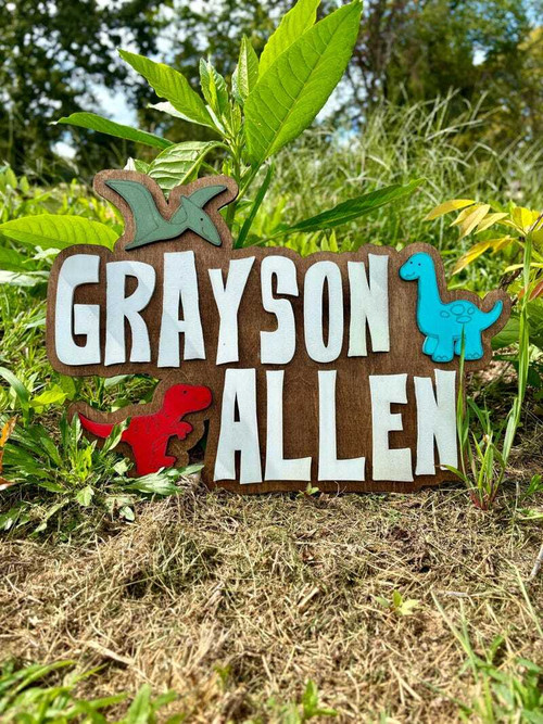 Dino-themed nursery name sign with cute dinosaurs, personalized with baby boy’s name; nursery wall decor or baby shower gift | Family Wall Decor CA