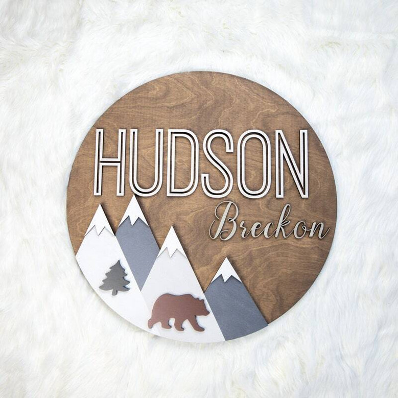 3D mountain woodland round wood nursery sign with personalized name in cursive, walnut stain, birch peaks, baby shower gift