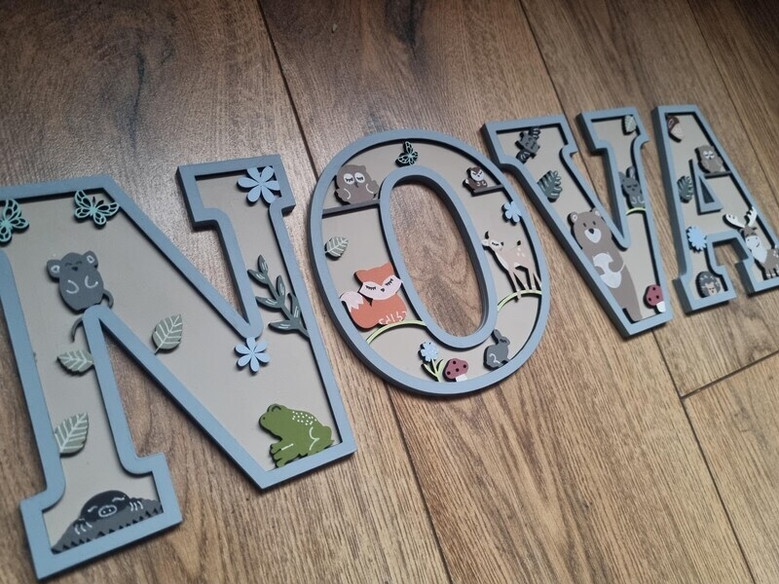 Woodland nursery animal wood sign letters, painted gray, cursive name with owl and moon, above changing table