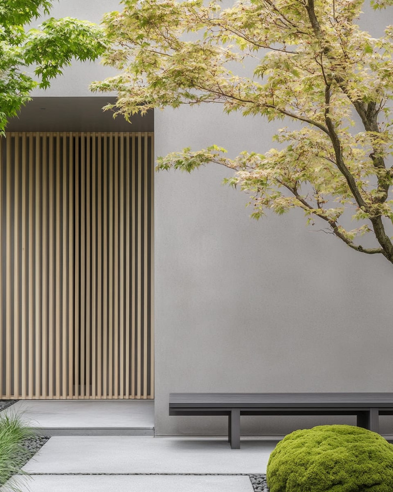 A serene Japandi front yard with a cohesive color palette, featuring a light grey exterior wall, natural blonde wood slatted screen, a minimalist dark grey bench, and subtle green Japanese maples and moss accents. A serene Japandi front yard with a cohesive color palette, featuring a light grey exterior wall, natural blonde wood slatted screen, a minimalist dark grey bench, and subtle green Japanese maples and moss accents.