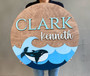 Whale-themed round wood nursery sign personalized with baby name, ocean wall decor plaque, thoughtful baby shower gift