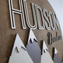 3D mountain woodland round wood nursery sign with custom name, sage and white accents, sans serif text, above crib decor